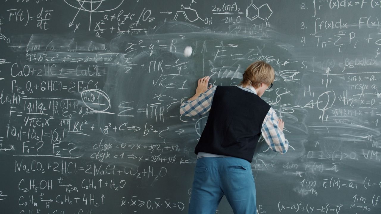 heros-img Person writing mathematical equations on a chalkboard, deep in study.
